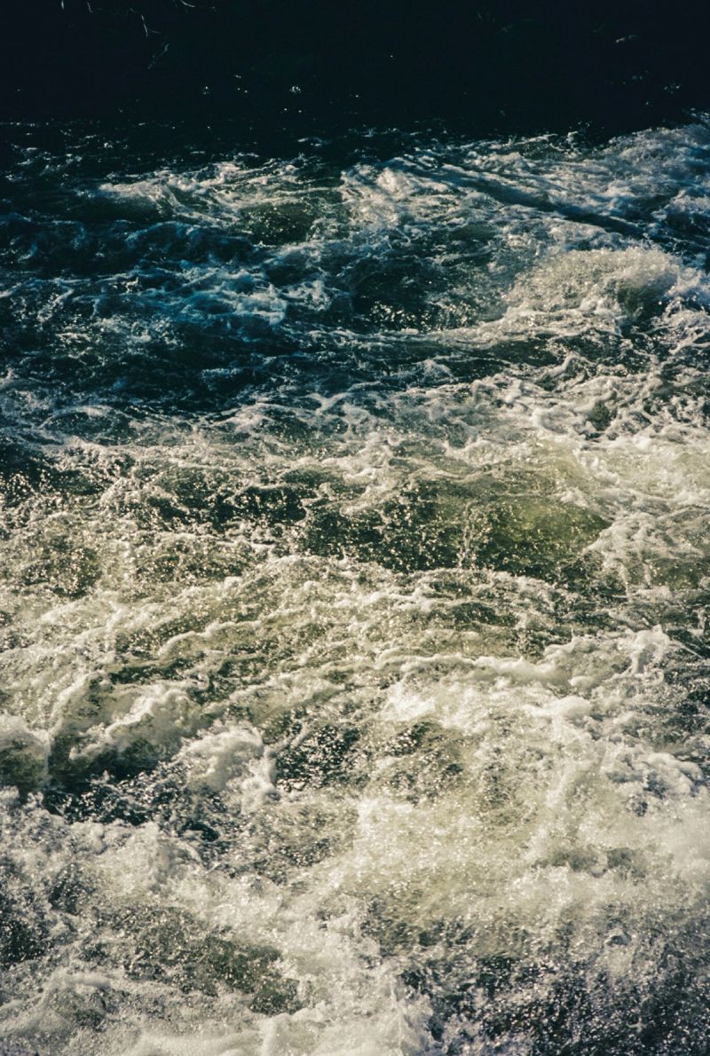 Churning ocean waves with white foam and dark water under sunlight