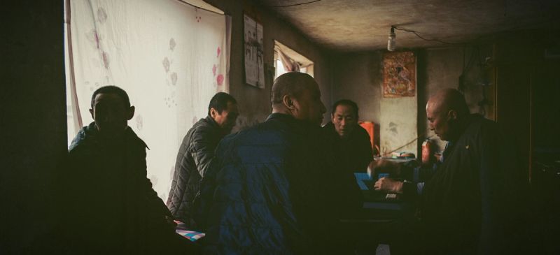 Men gathered in a dimly lit rustic interior, capturing authentic documentary moments for the Toyota Start your Impossible campaign.