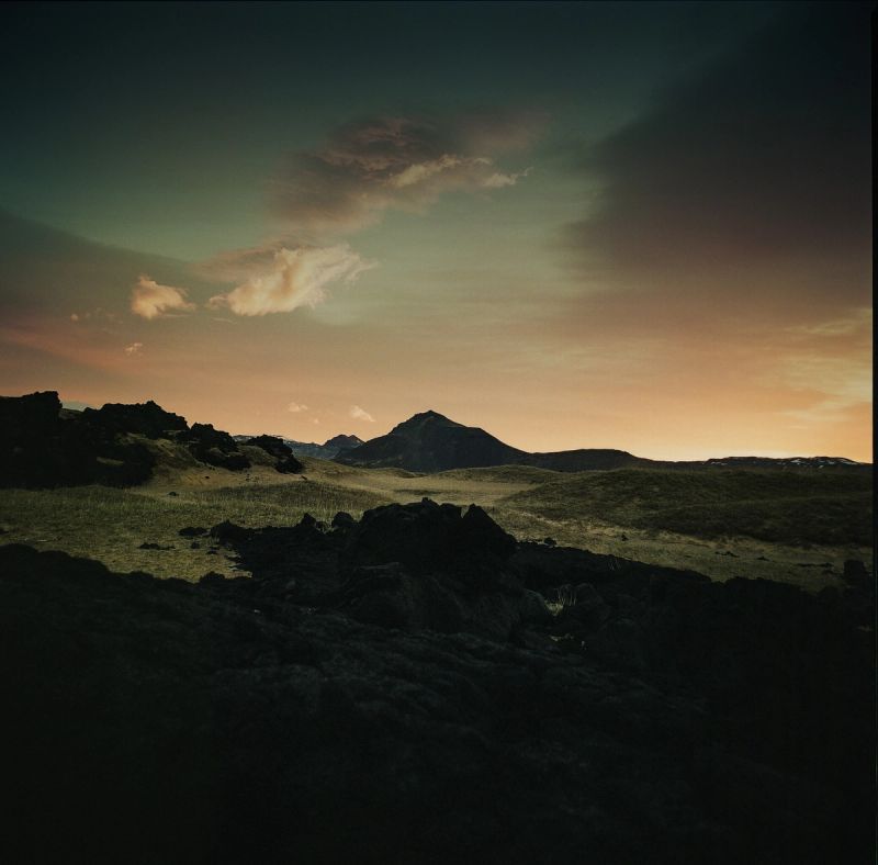 Icelandic mountain landscape at sunset with rocky foreground and dramatic clouds.