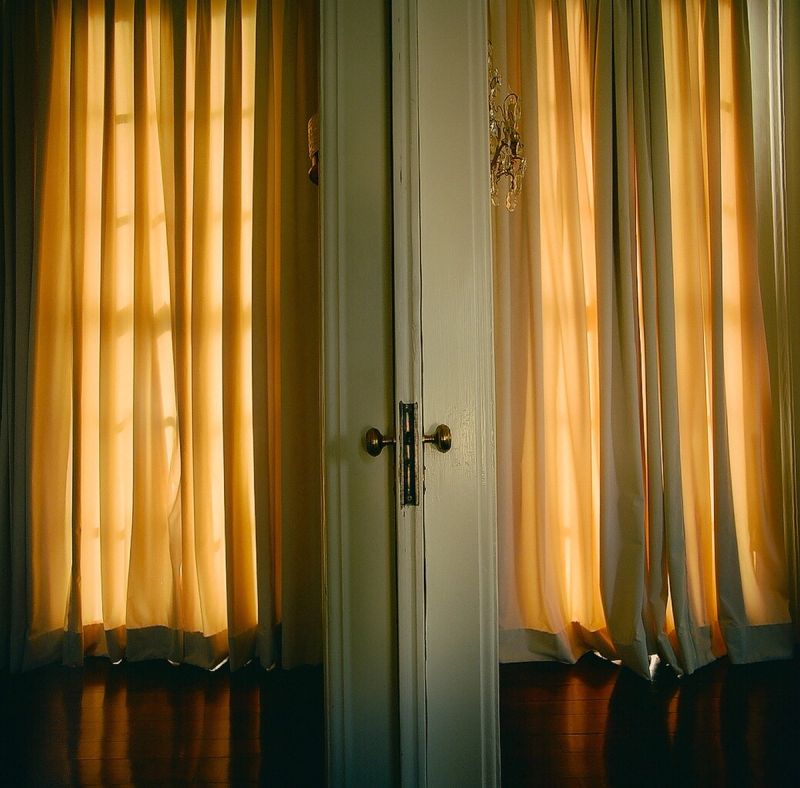 Warm golden light filters through sheer curtains behind white French doors in Atlanta.