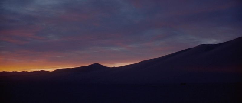 Silhouetted desert mountains at twilight with purple and orange sky