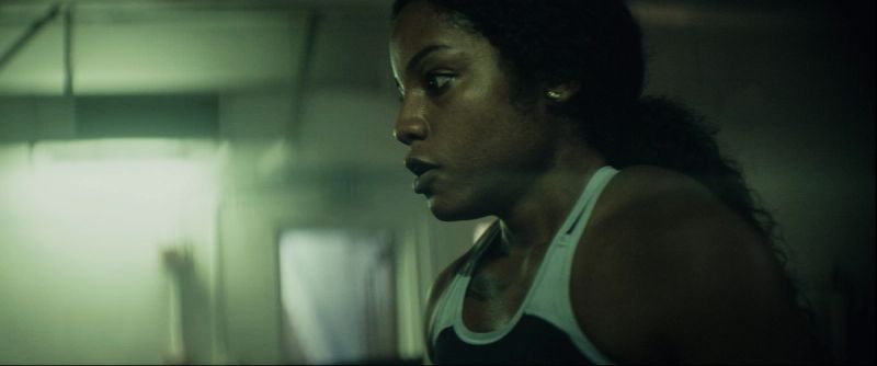 Cinematic profile of athlete Jen Welter in athletic wear inside gym with moody lighting for Eastbay ConqHer.