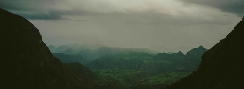 Layered green mountain ridges under moody overcast sky