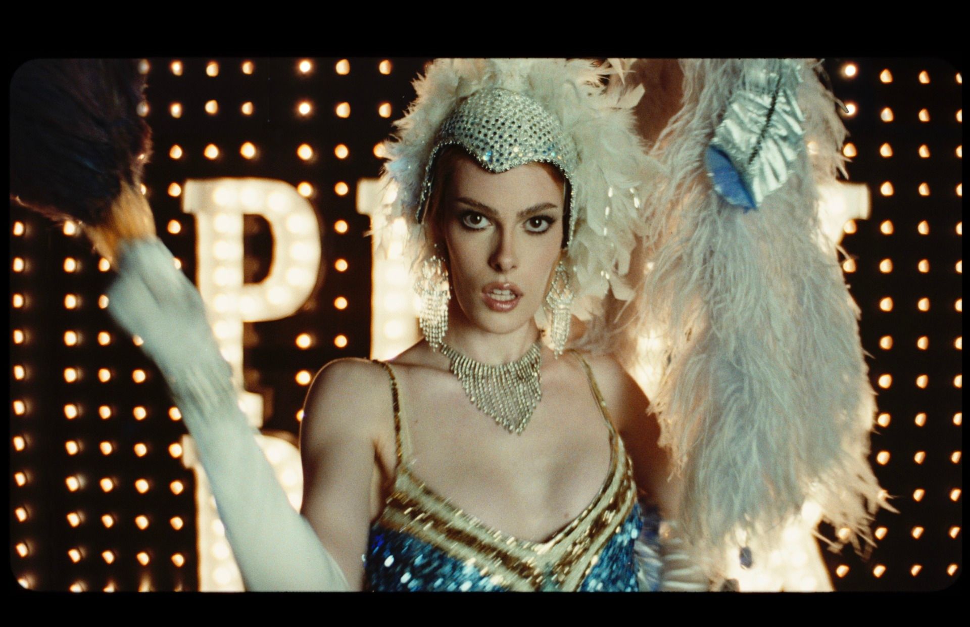 Sharon Stone in feathered flapper costume with marquee lights behind