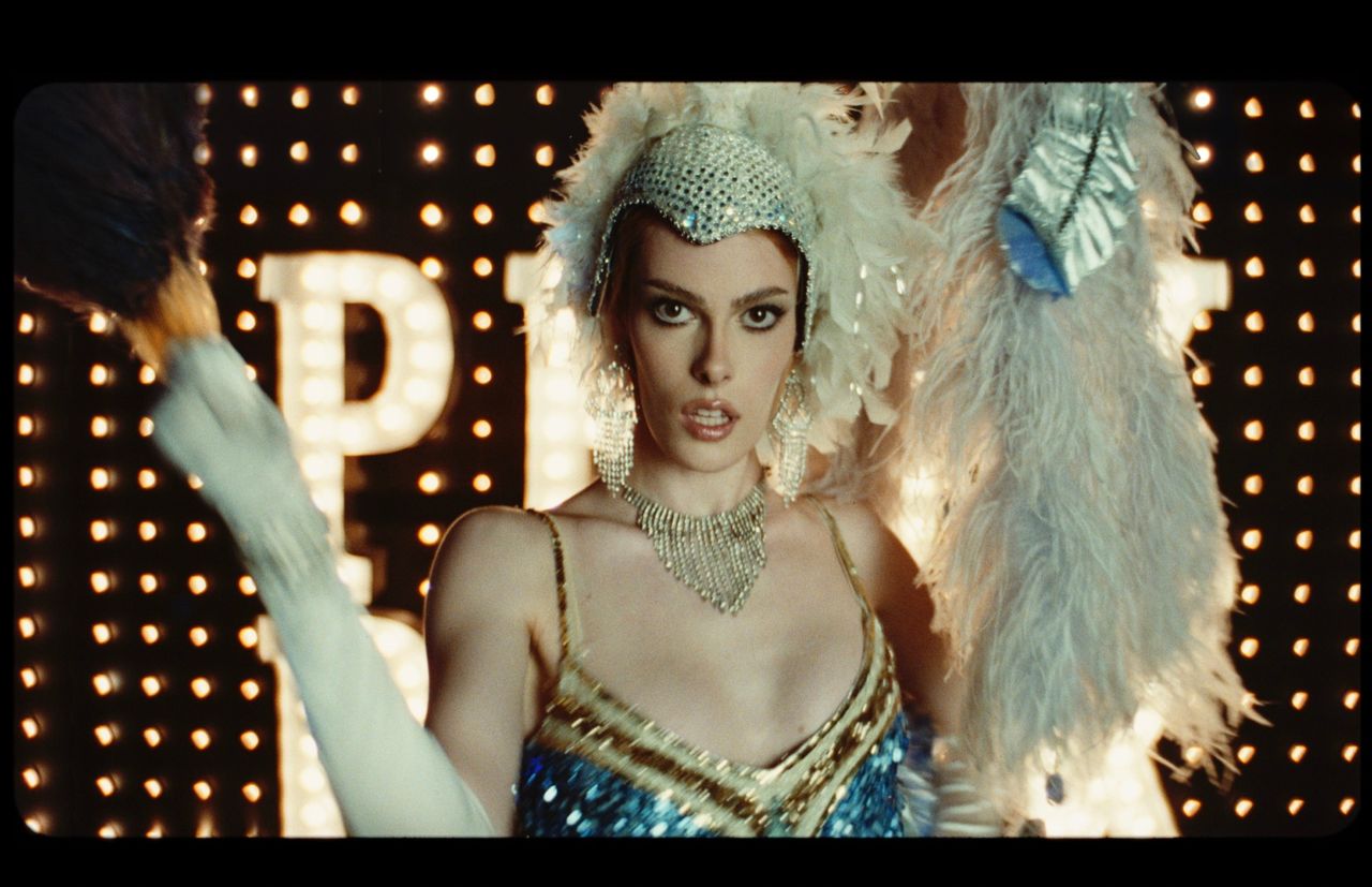 Sharon Stone in feathered flapper costume with marquee lights behind