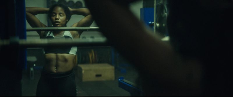 Jen Welter posing in gym mirror reflecting athletic form during women's football campaign shoot.