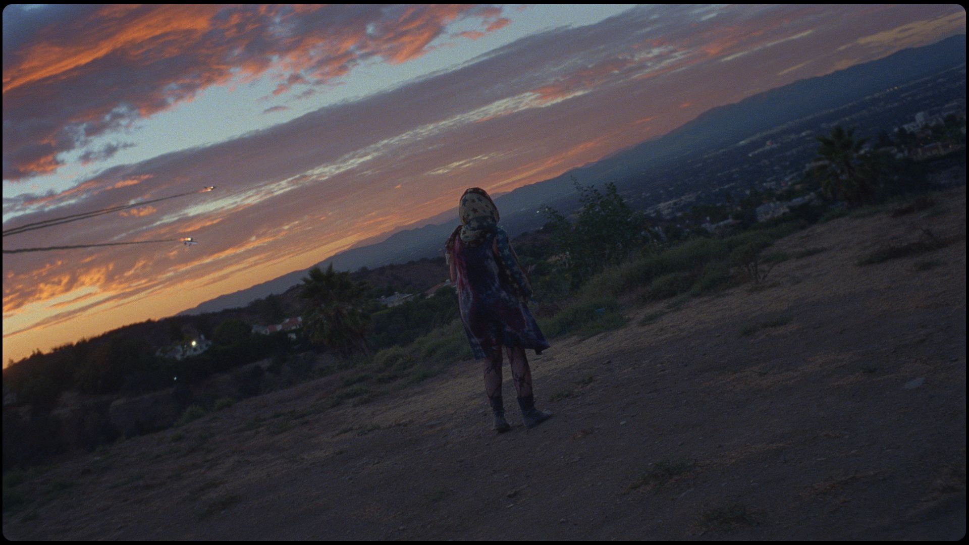 Cinematographer Ian Rigby captures a lone figure on a hilltop at sunset, overlooking a cityscape.