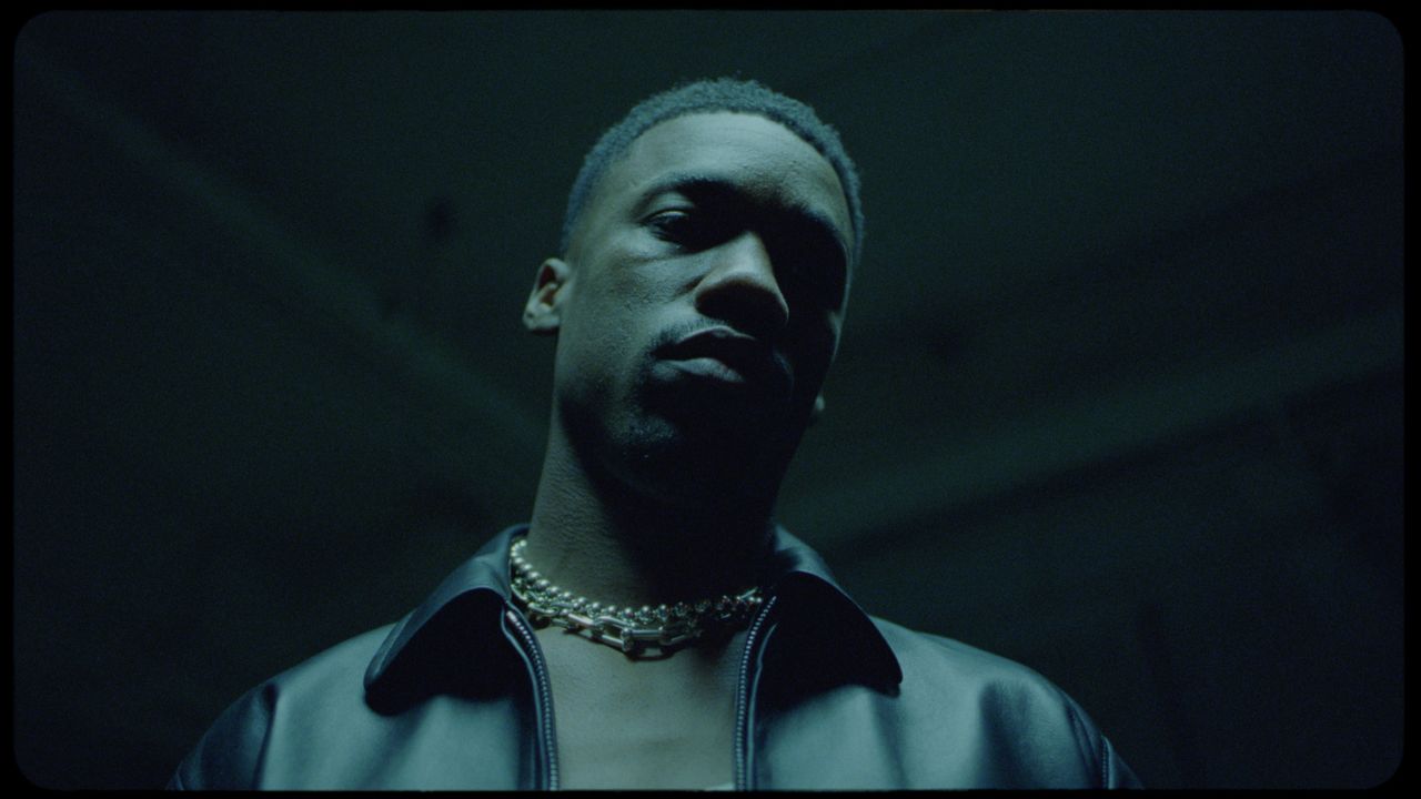 Giveon in moody cinematic portrait with layered chains and leather jacket