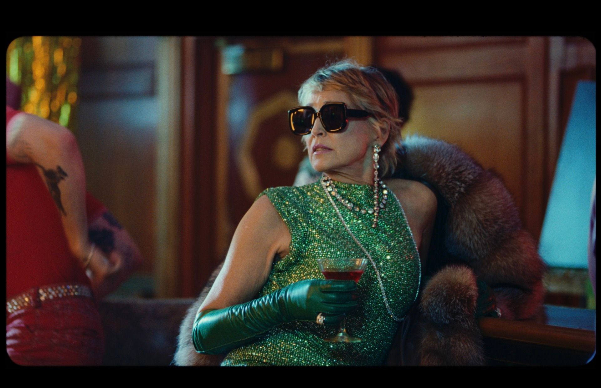 Sharon Stone in green sequin dress and sunglasses holding cocktail at Death Valley High