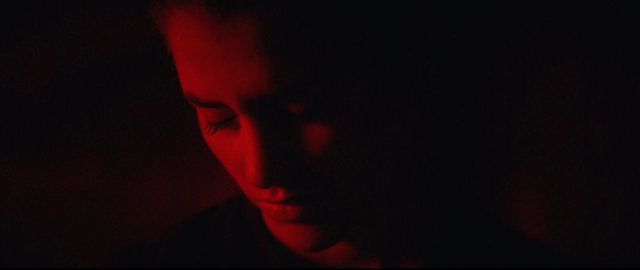 Close-up of Olympic wrestler Helen Maroulis in dramatic red lighting looking down.