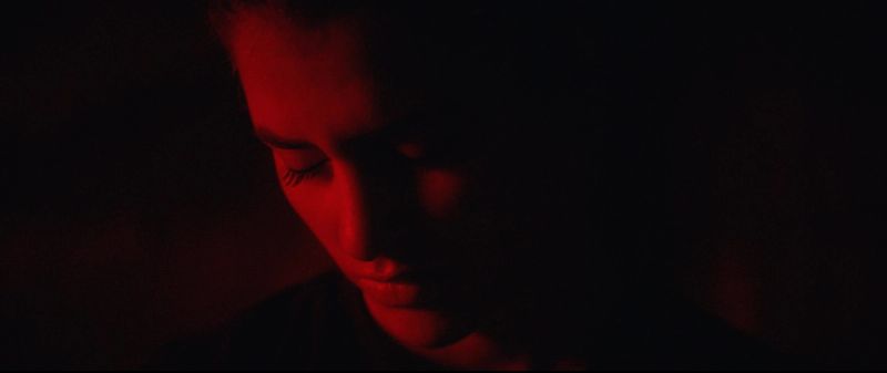 Close-up of Olympic wrestler Helen Maroulis in dramatic red lighting looking down.
