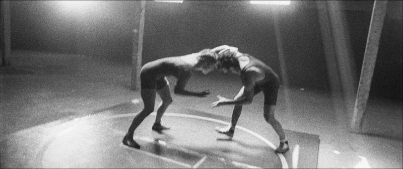 Two Olympic wrestlers locked in a stance on a wrestling mat, black and white film photography.