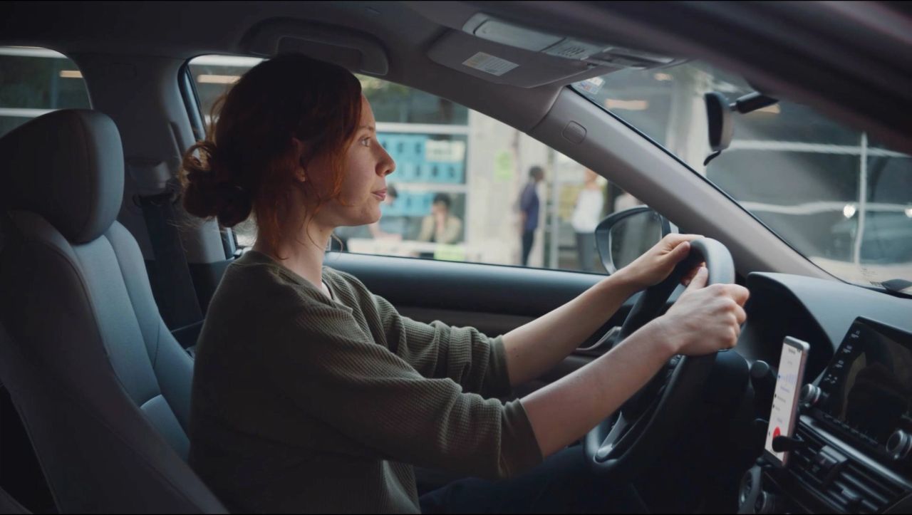 Side view of a woman driving a car with hands on the steering wheel.