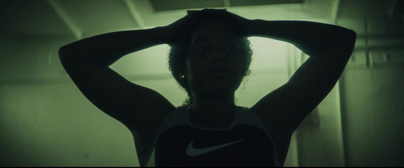 Jen Welter posing with hands behind head in a dimly lit locker room setting.
