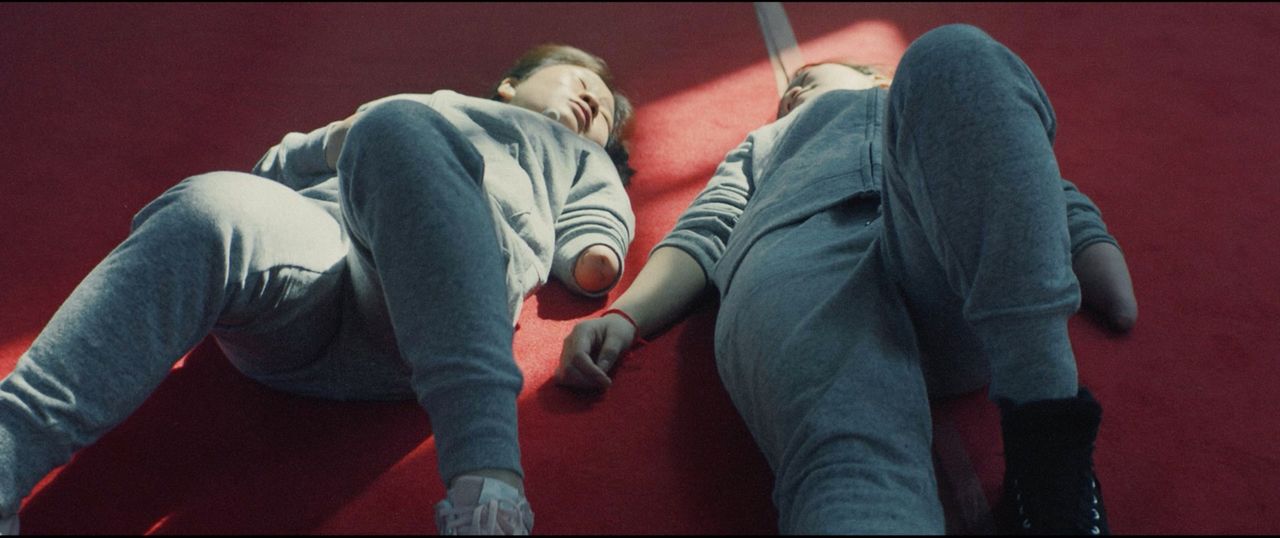 Two children lying on red carpet in cinematic film photography