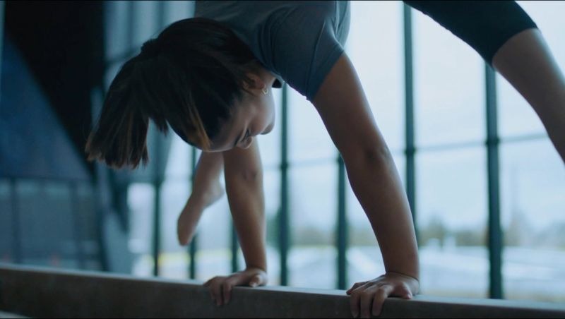 Woman performing yoga pose on balance beam in modern studio