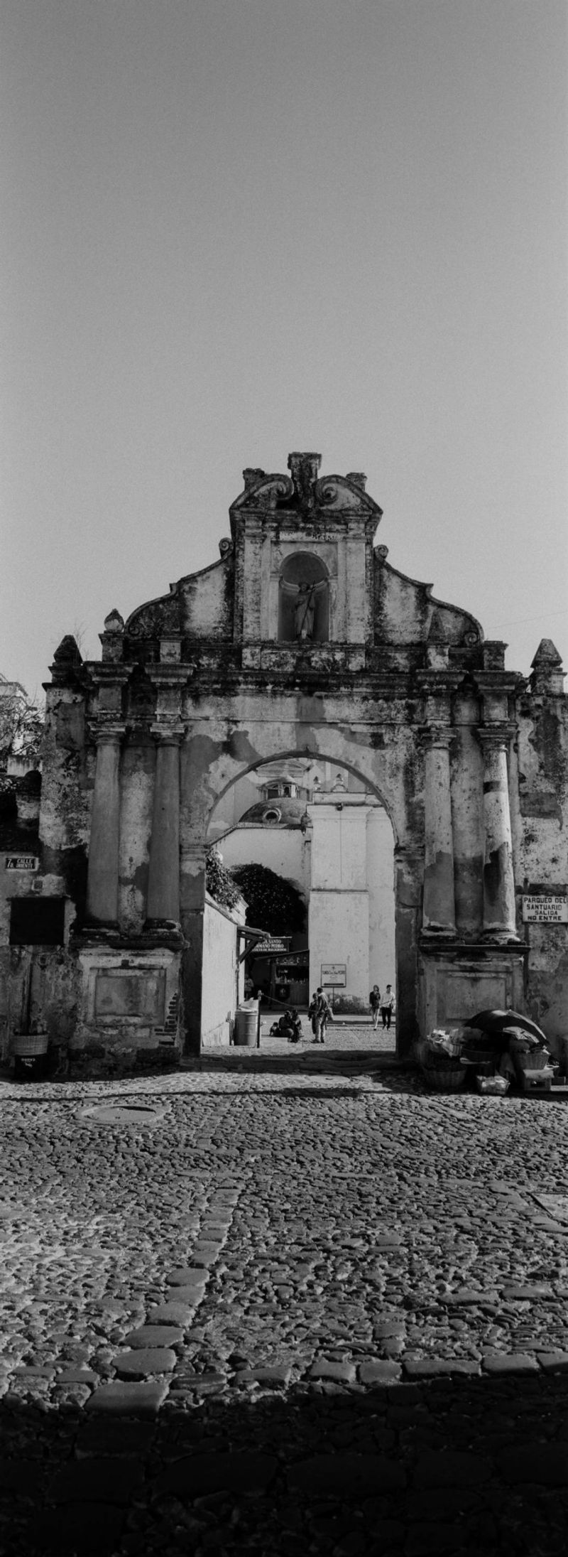 Weathered colonial stone archway and cobblestone street captured on film in Guatemala.