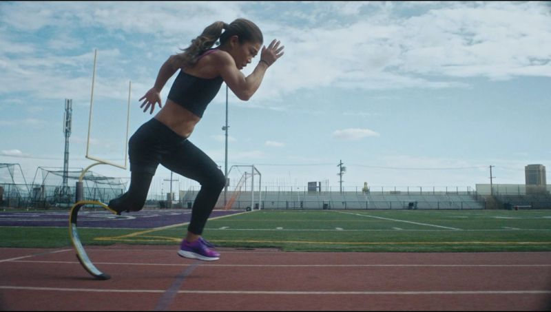 Female athlete sprinting on track with running blade prosthetic leg