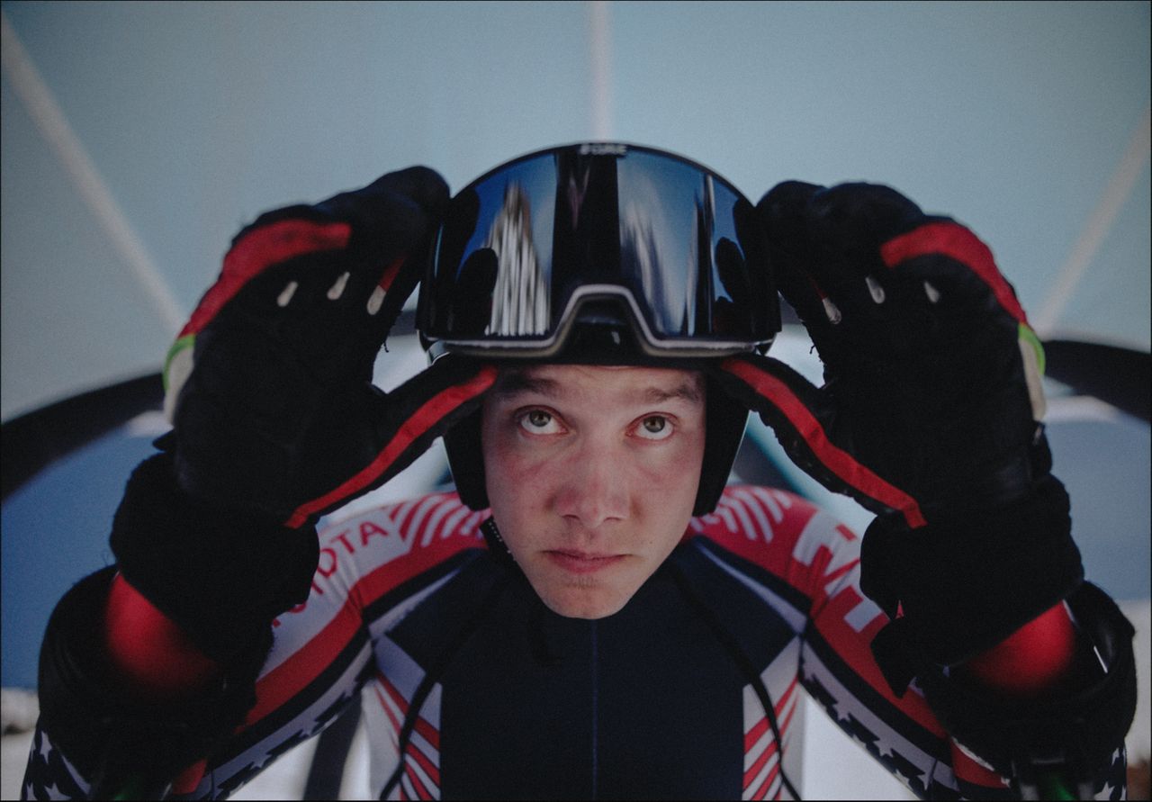 Athlete adjusting ski goggles on helmet before competition