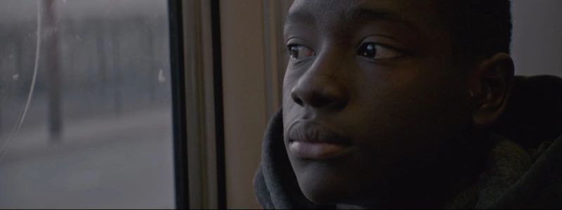 Young boy gazing out a train window in muted natural light
