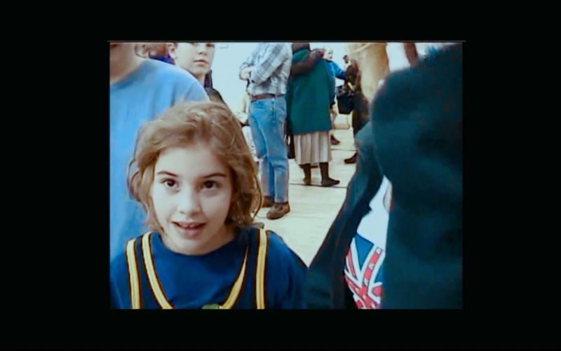Young wrestler Helen Maroulis in blue shirt and yellow suspenders at a crowded event.