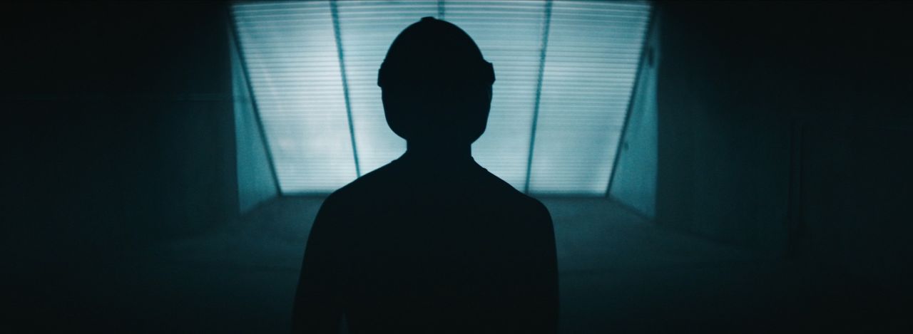 Silhouette of a skydiver facing a bright tunnel light in VR experience.