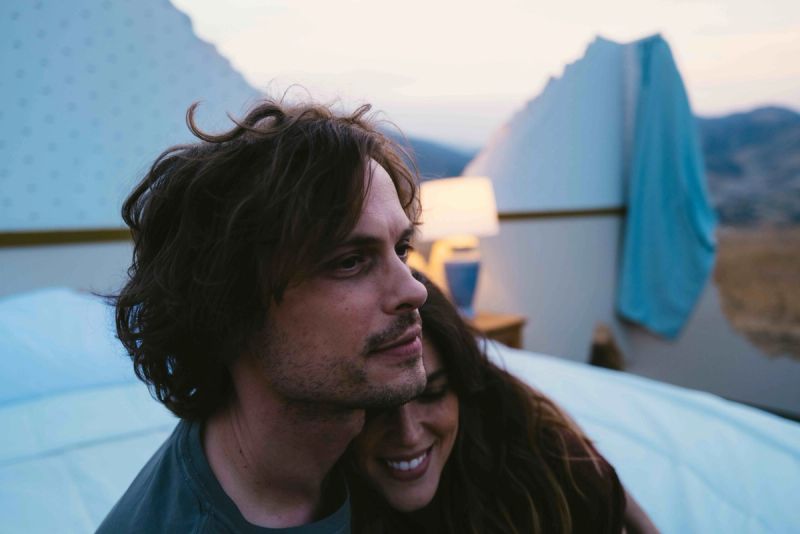 Couple embracing in a glamping tent at dusk with mountains in background