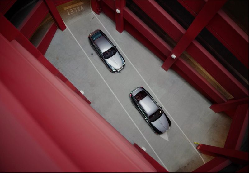 High angle view of two silver Rolls-Royce sedans parked in a valet area with red structural beams.