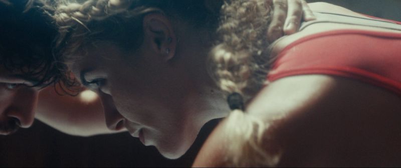 Close-up profile of Olympic wrestler Helen Maroulis in red singlet looking down with hand on shoulder.
