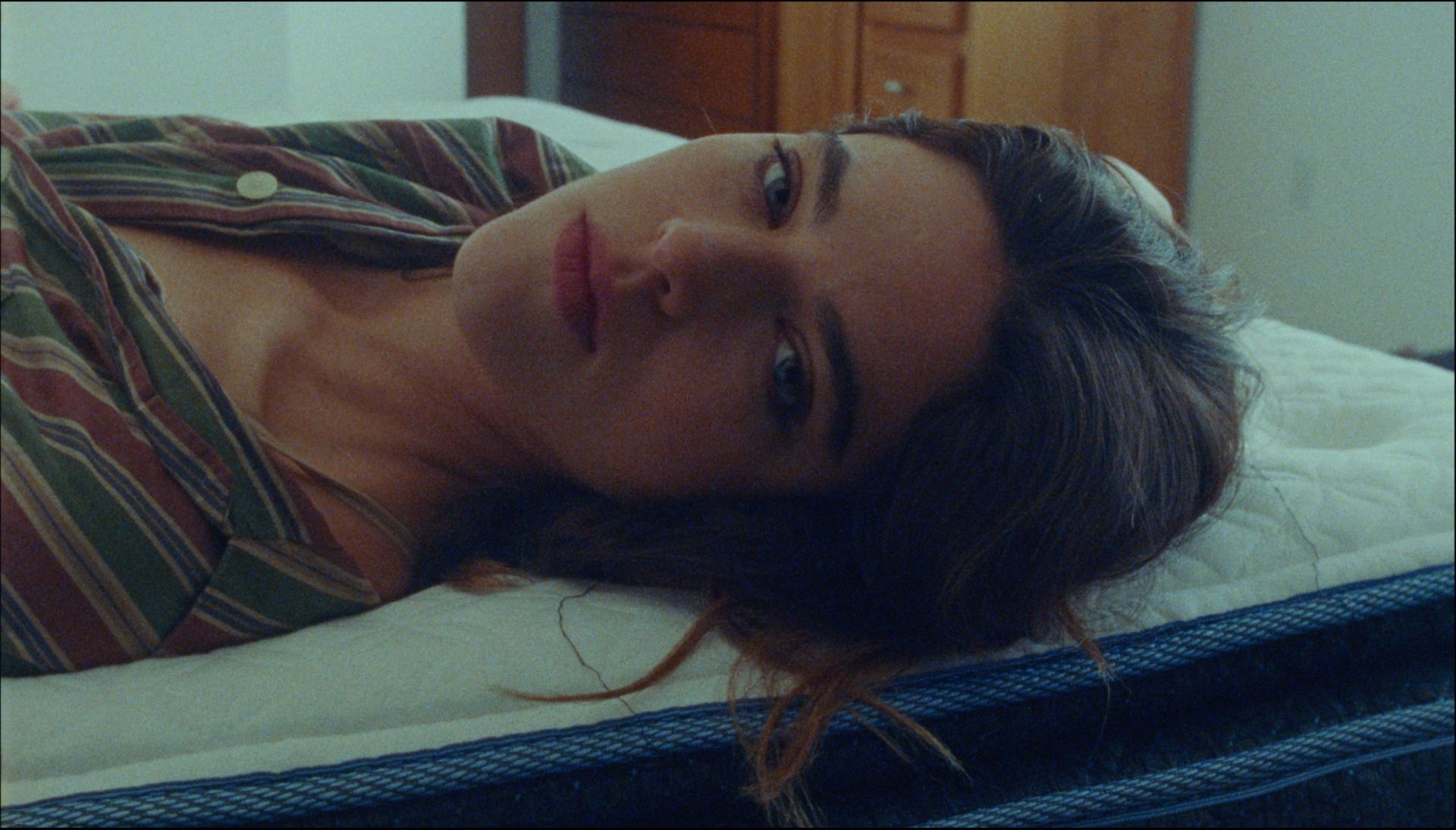 Woman lying on bed in striped pajamas, soft natural lighting