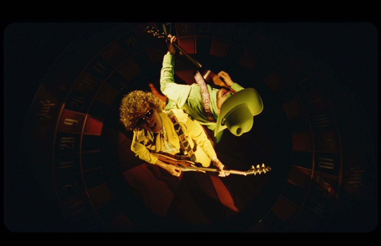 Orville Peck and Beck playing guitars inside a roulette wheel in Death Valley High