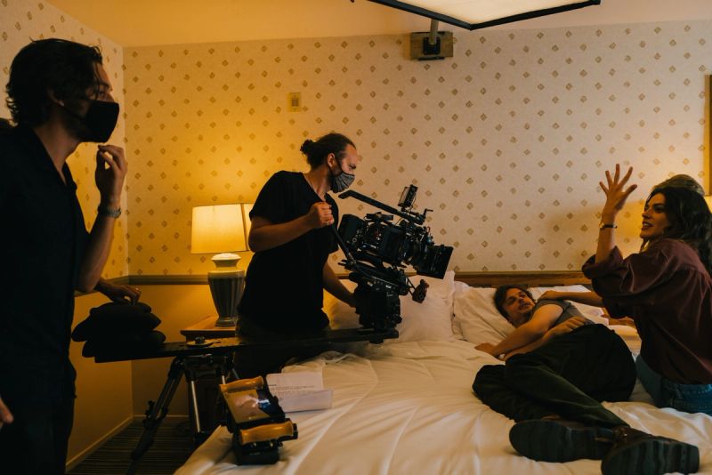 Behind-the-scenes on a film set in a hotel room with camera crew and actors