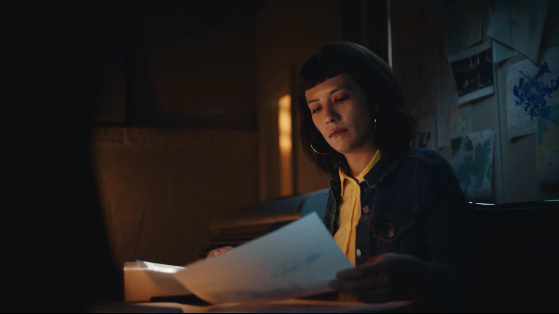 A woman reviews documents in a dimly lit office space with cinematic lighting.
