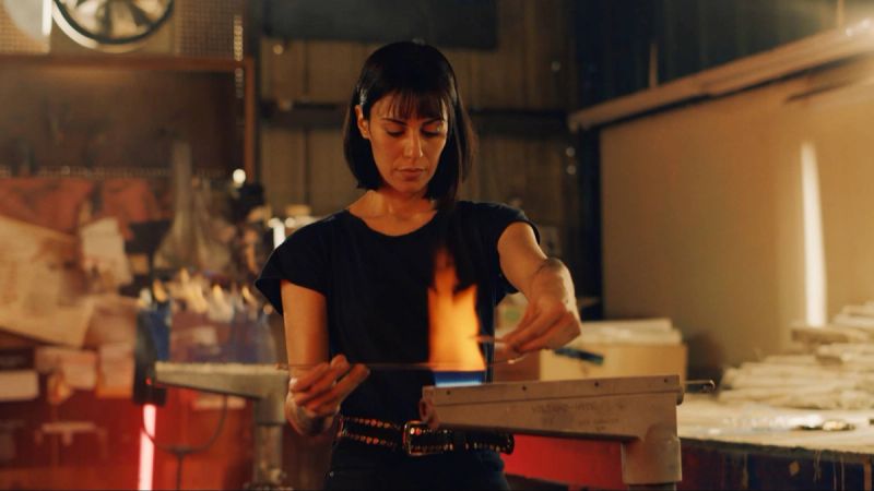 Woman working with molten glass in a workshop setting