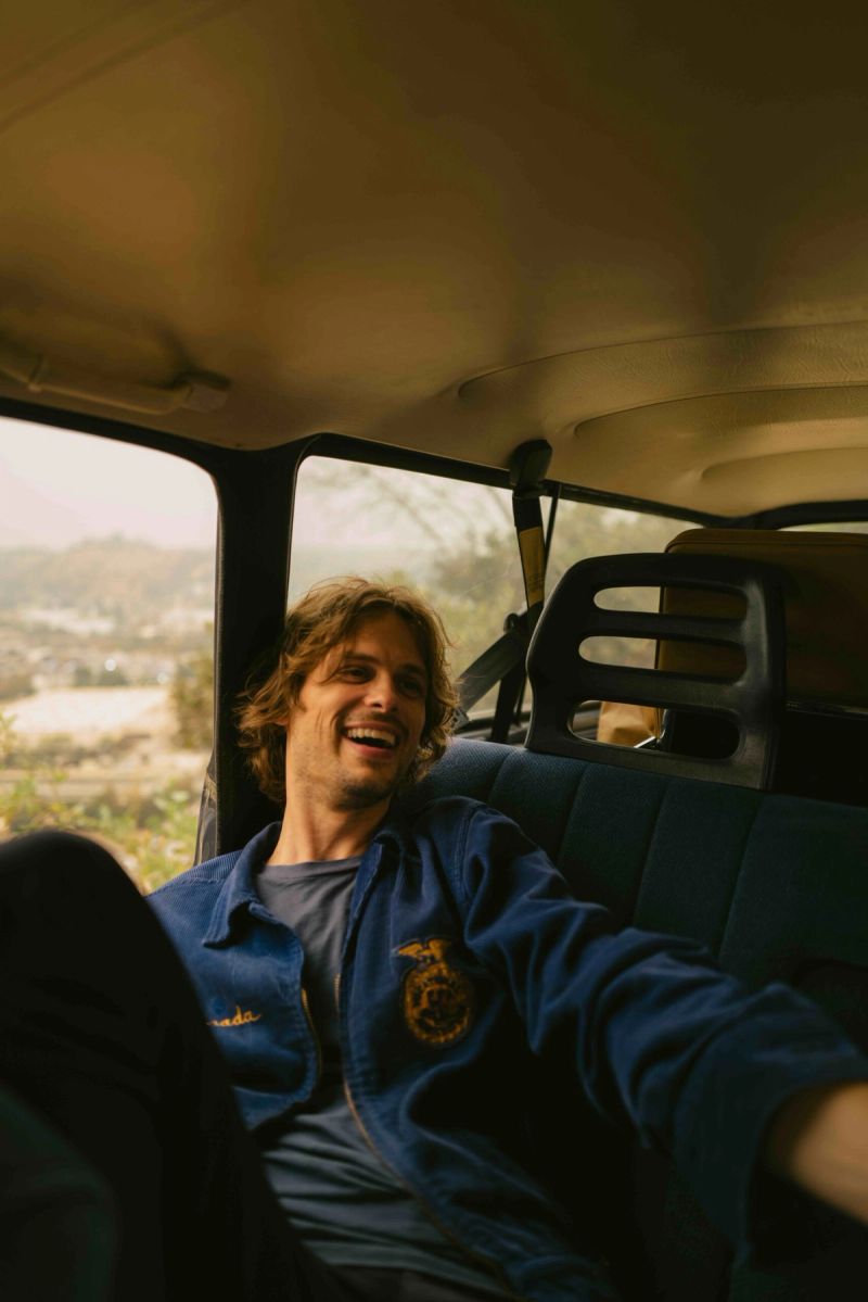 Actor laughing in vintage car interior during Future Islands Moonlight shoot