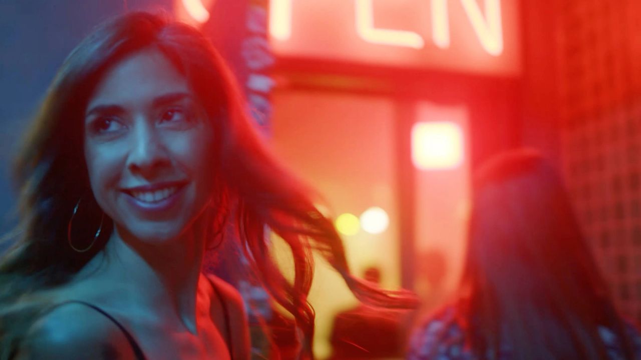 Woman smiling under red neon light in urban night setting