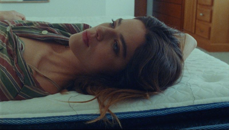 Woman lying on a bed in striped pajamas, soft natural lighting