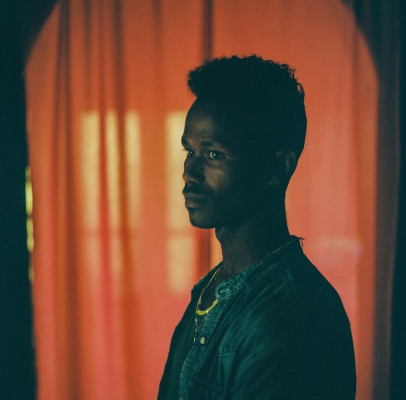Profile portrait of a man in denim against warm orange curtains, Lufthansa Airlines cinematography.