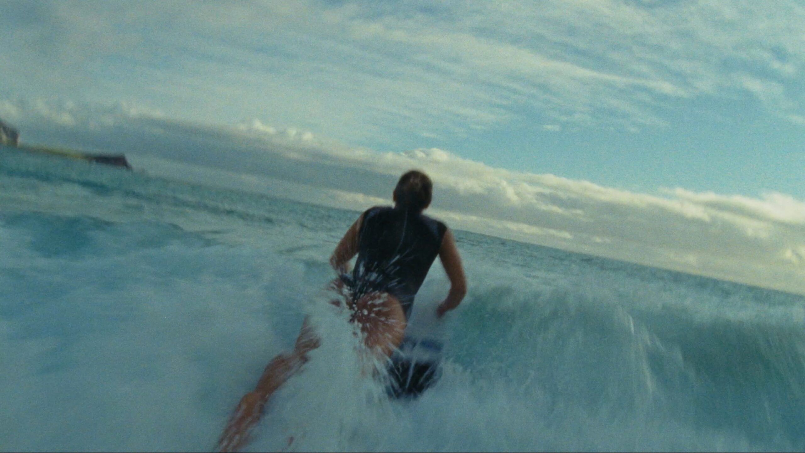 Surfer riding a wave in ocean under cloudy sky