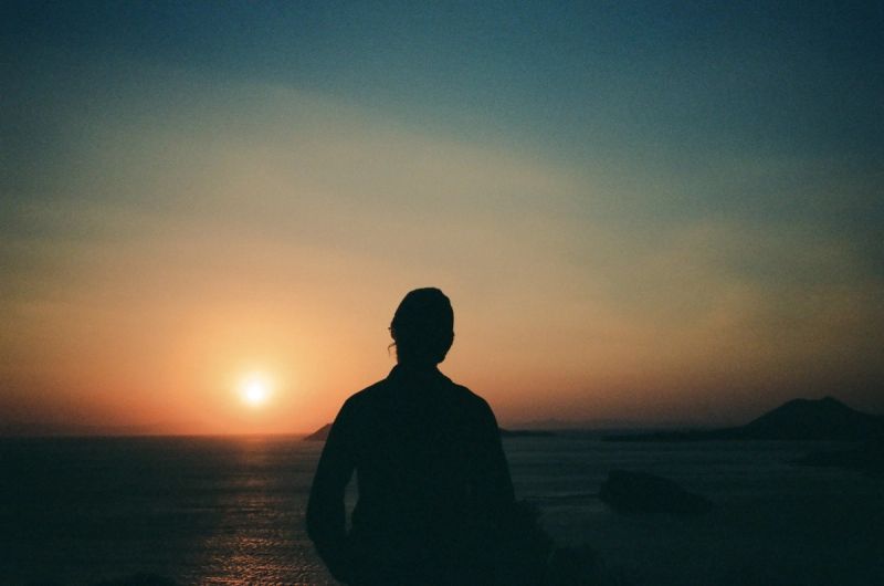 Silhouette of a person watching the sunset over the ocean, captured on Kodak Portra 800 film.