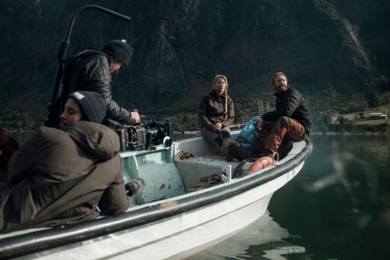 Cinematographer operating camera on a boat with actors in Patagonia fjord.