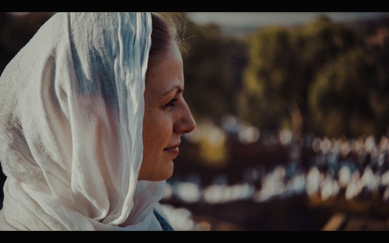 Woman in white headscarf gazes over blurred crowd in Ethiopia