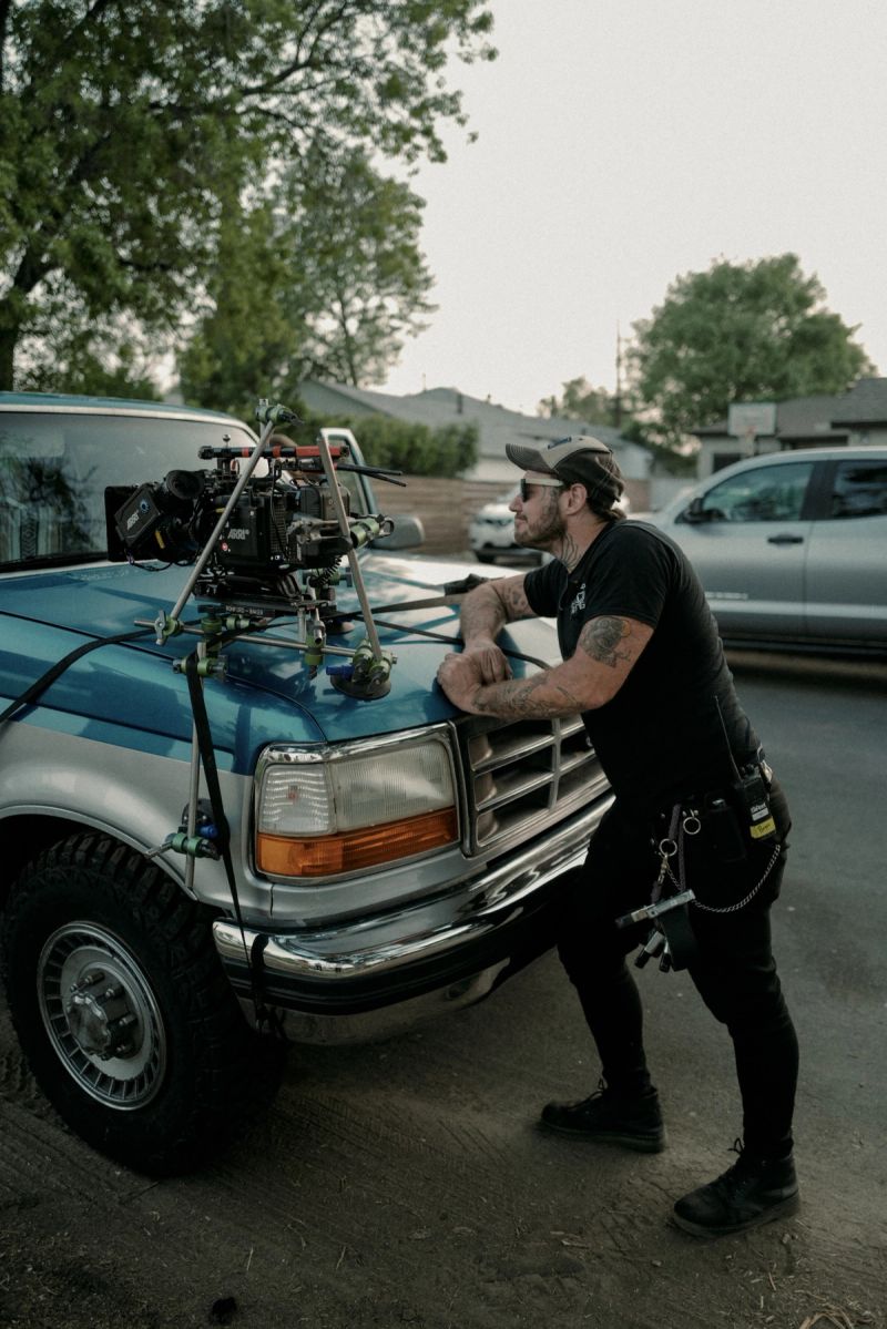 Ian Rigby leaning on a blue truck with a mounted camera rig during the Zara Larsson – End of Time shoot.
