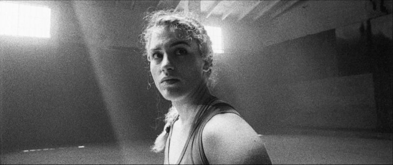 Olympic wrestler Helen Maroulis looks over her shoulder in a sunlit gym during the EastBay ConqHer project.