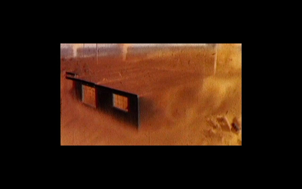 Dusty desert landscape with a black bench in foreground