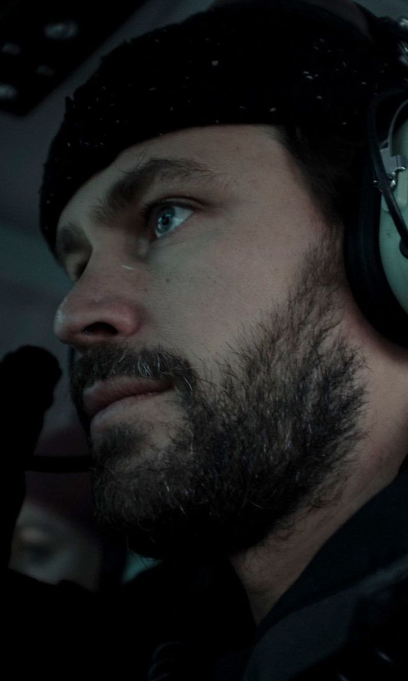 Cinematographer Ian Rigby on set with headphones, focused expression in dim lighting