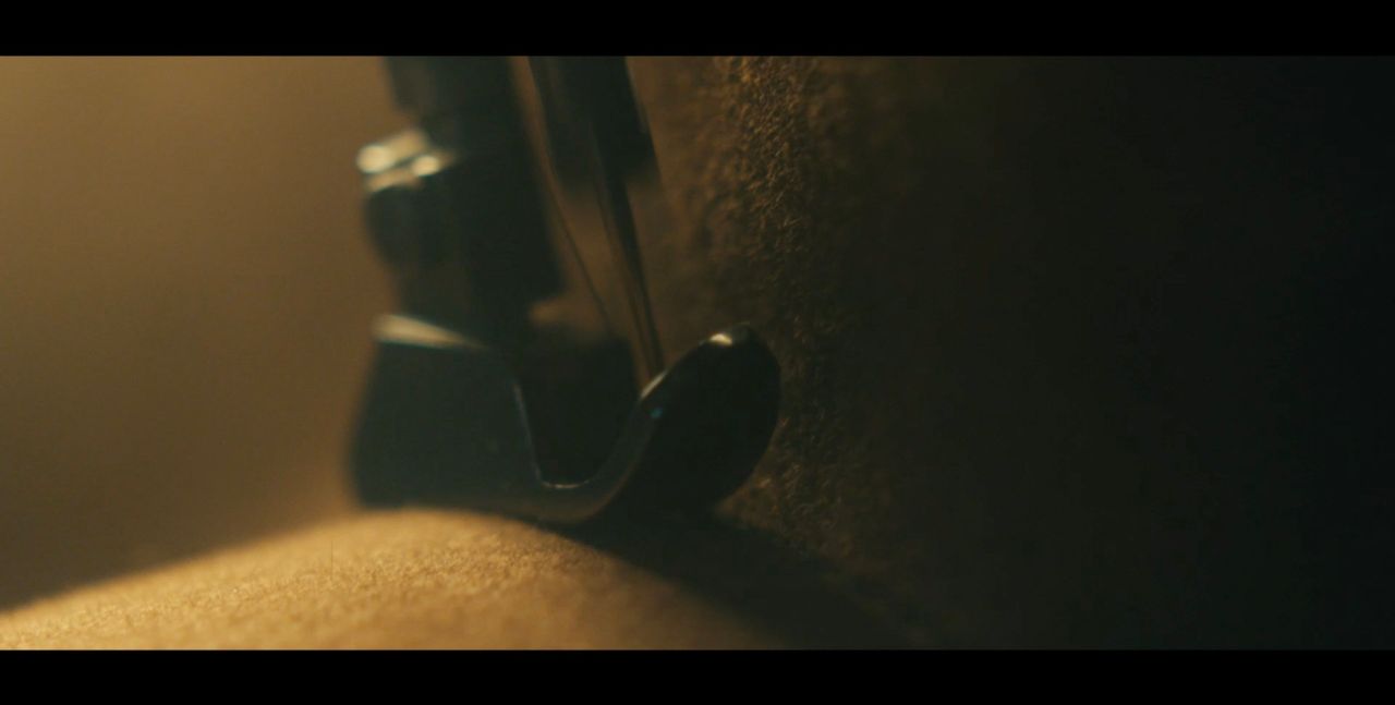 Close-up cinematography detail of a vehicle interior mechanism against textured leather surface.
