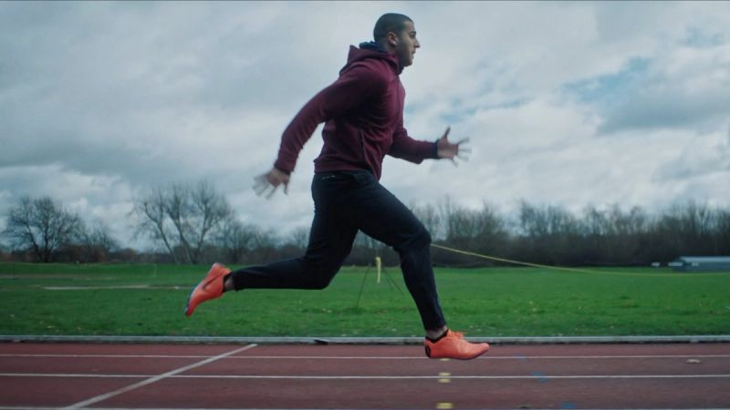 Athlete mid-stride sprinting on a track under cloudy skies