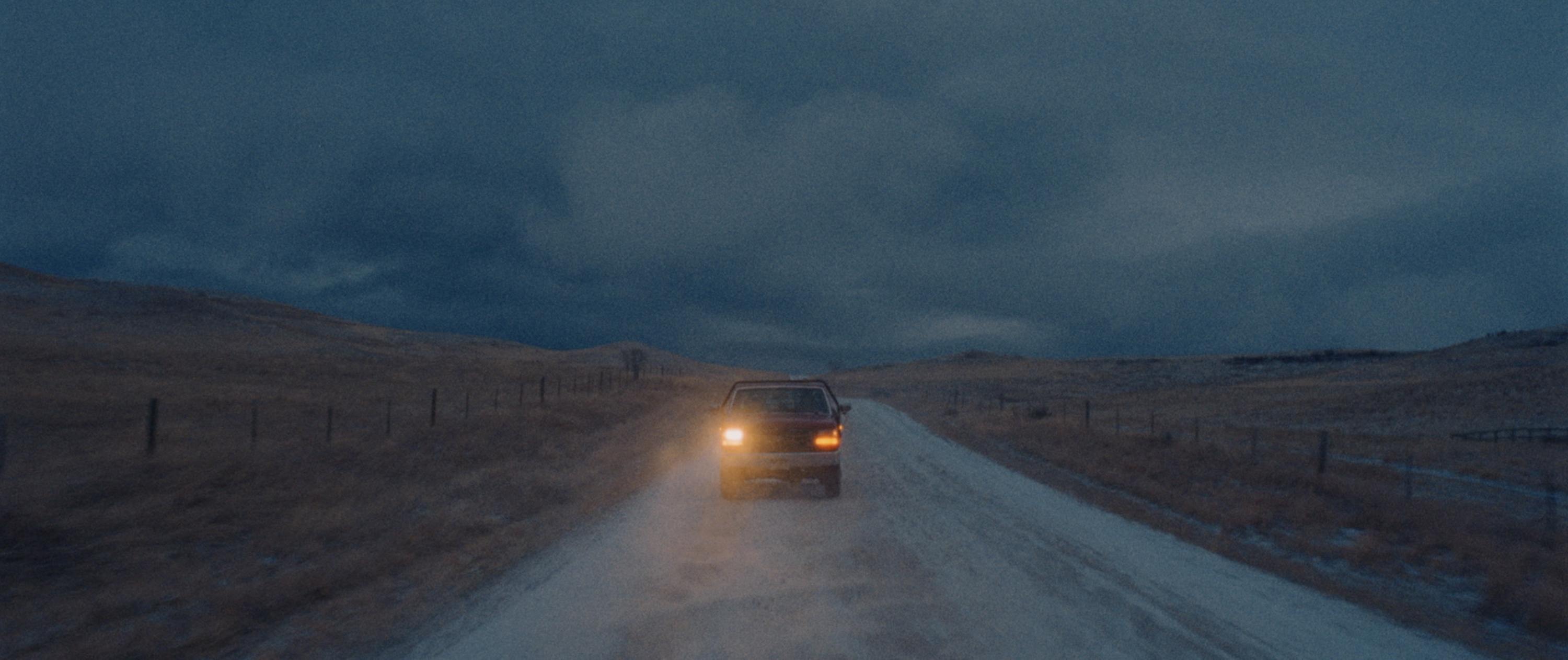 Car driving on a rural road at dusk in Montana