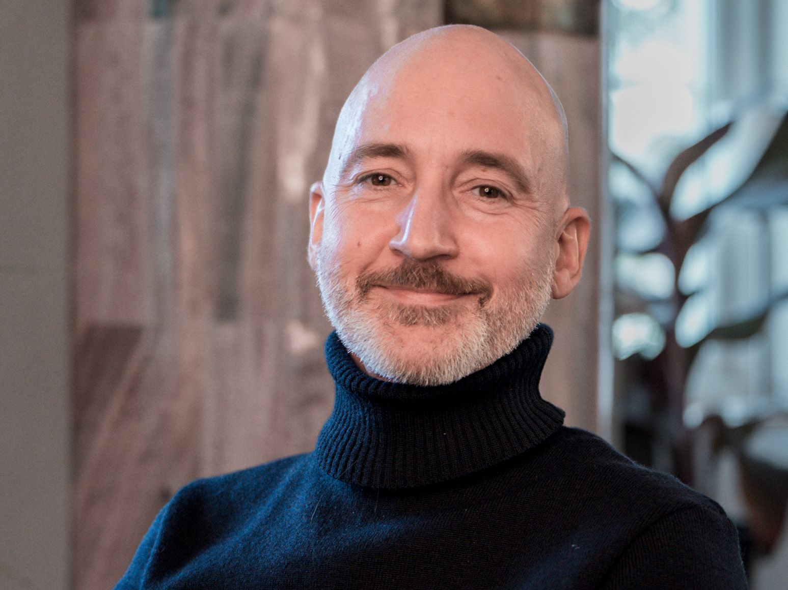 Porträtt av en konsult inom ledarskap, personen är inomhus och tittar in i kameran och ler.